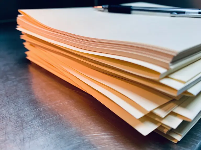 A stack of printed procedures on a stainless steel counter